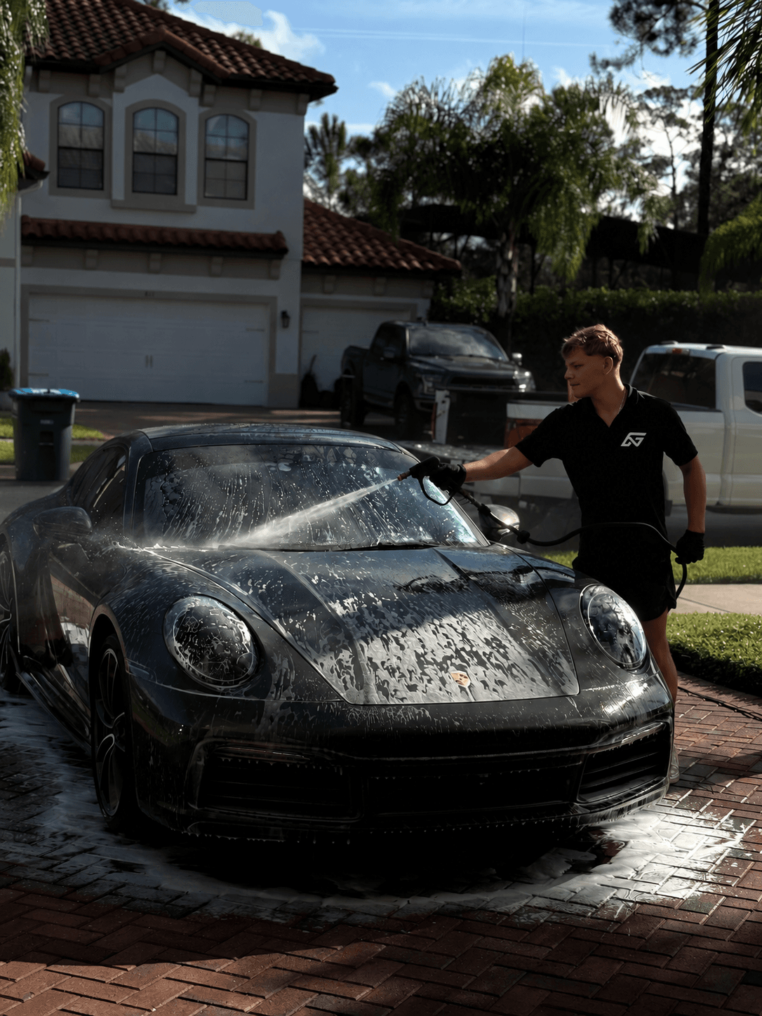 Ethan, founder of Need For Clean, washing a Porsche in a customer’s driveway